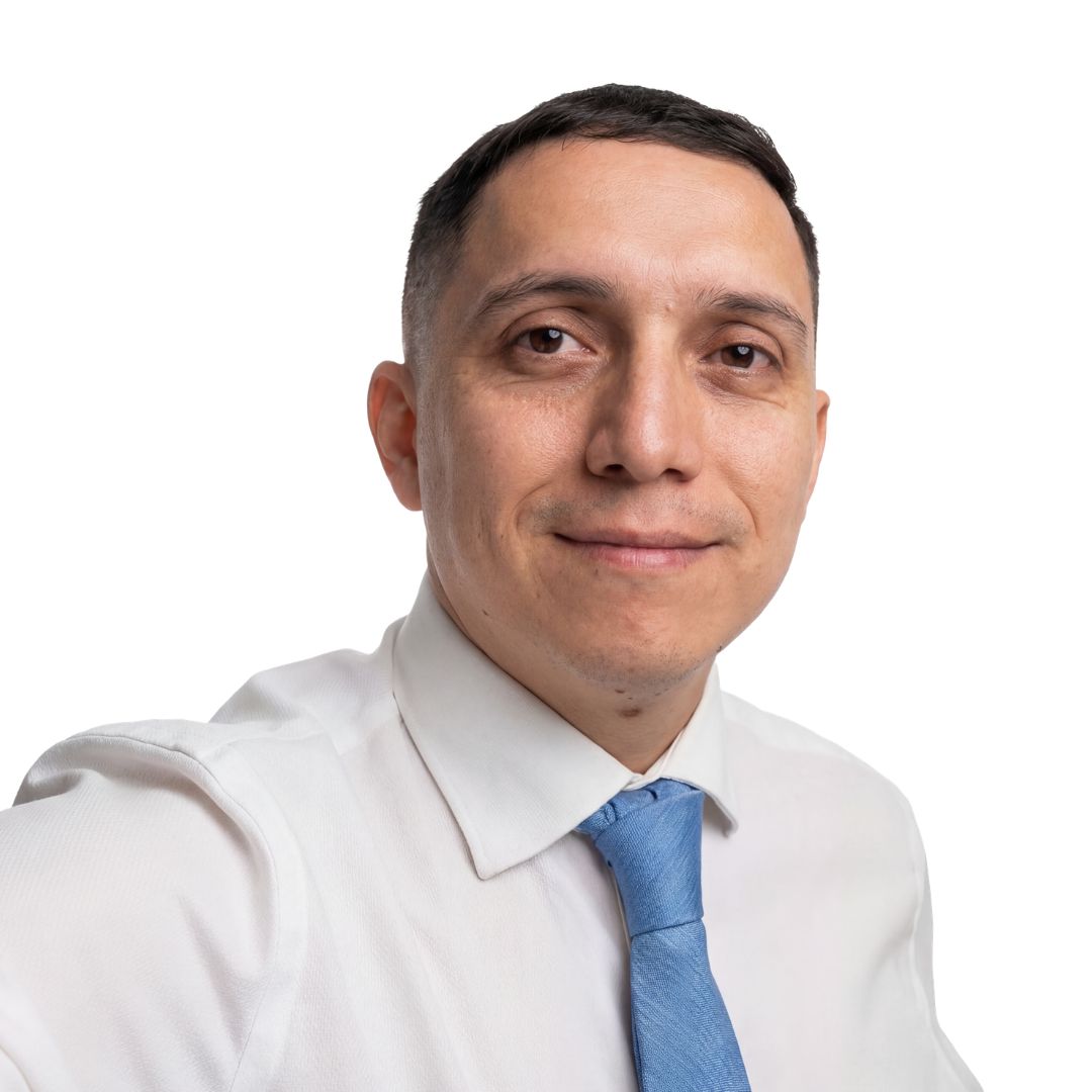 Woman with long brown hair and blue eyes smiling, wearing a black jacket over a white top.