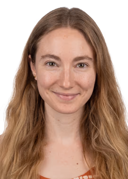 Smiling woman with long wavy light brown hair and light skin, wearing a brown top.