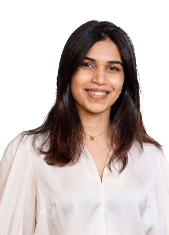 Smiling young woman with long dark hair wearing a white blouse and a gold necklace.