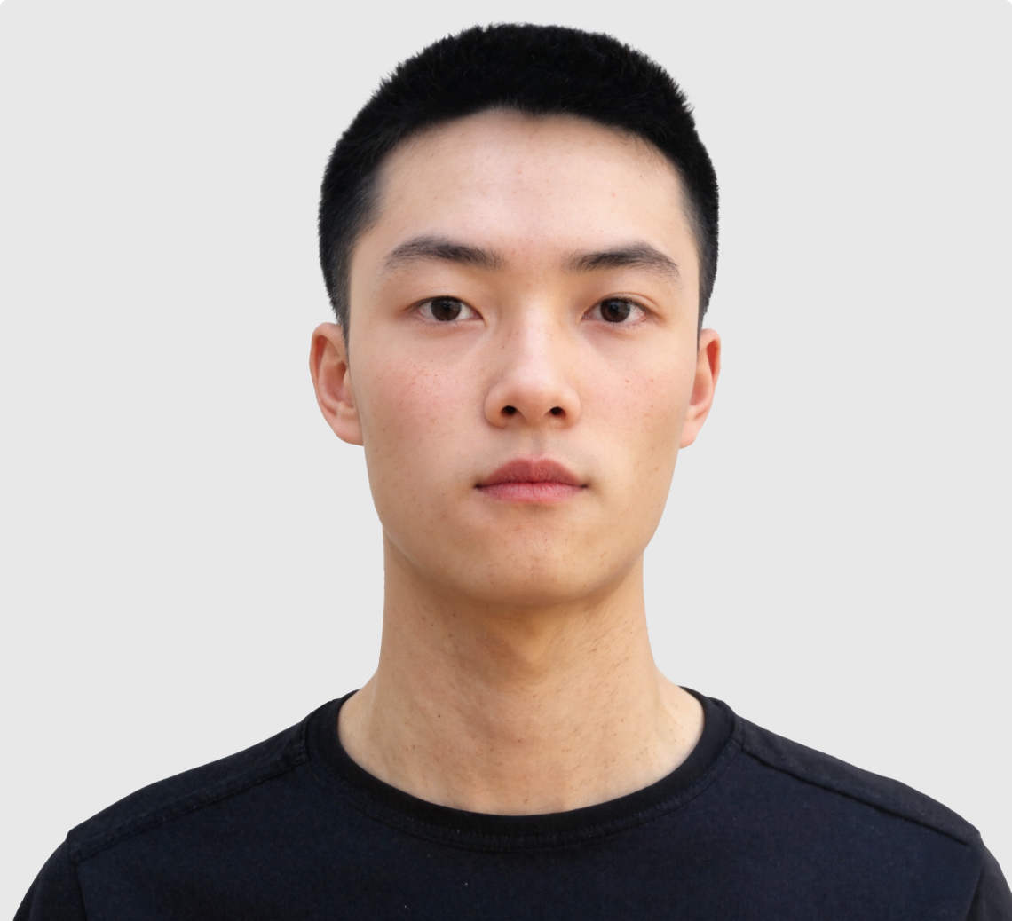 Portrait of a young man with short black hair wearing a black shirt against a light background.