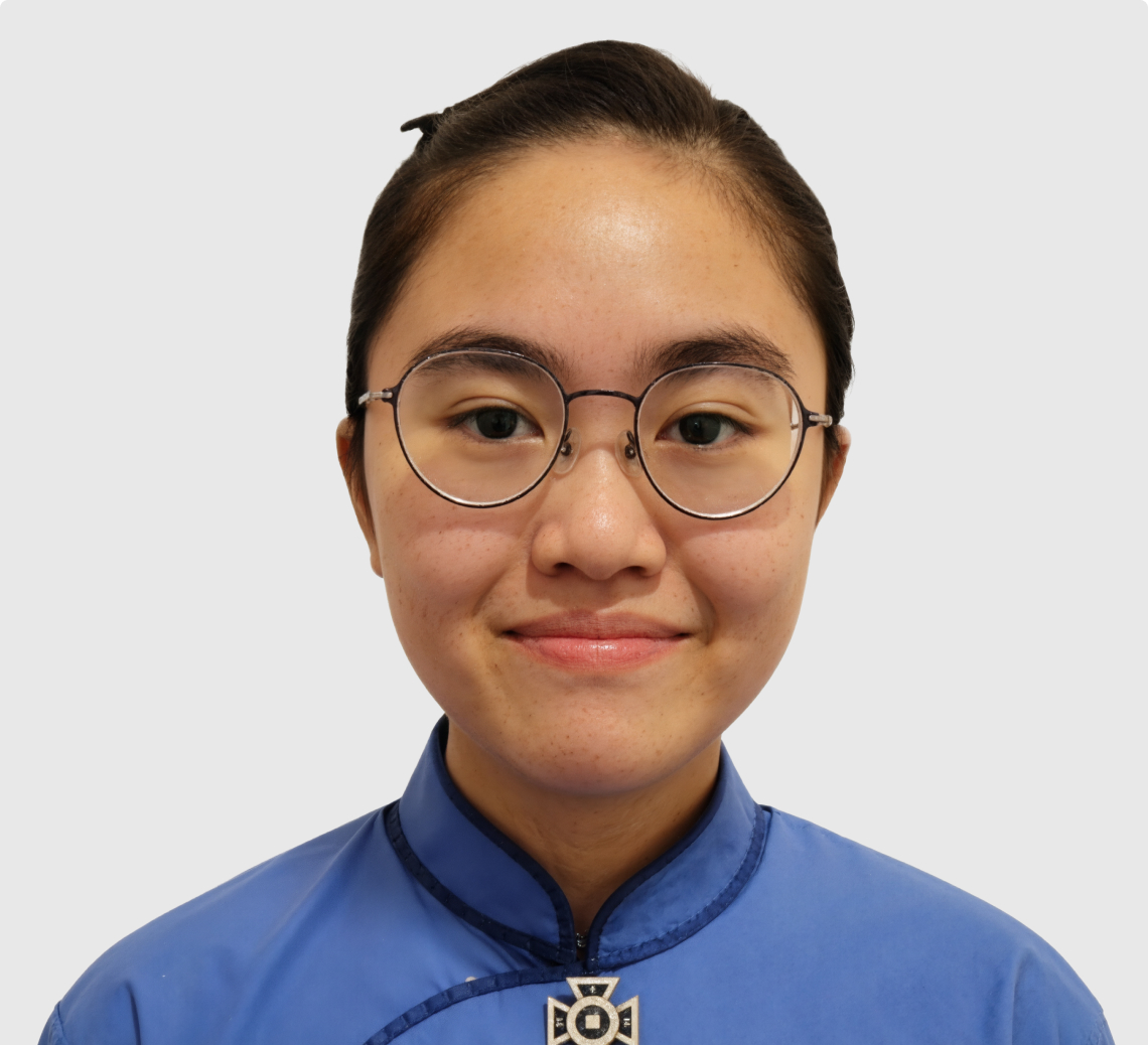 Smiling young woman with round glasses and hair tied back wearing a blue traditional-style top.