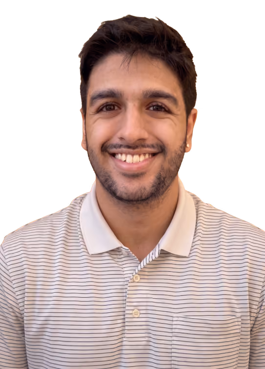 Smiling man with brown hair and beard wearing a purple buttoned shirt.