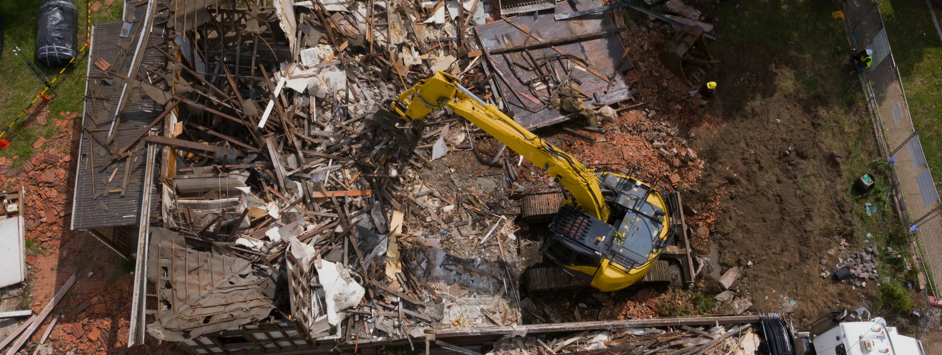 Bagger demoliert Haus – Luftaufnahme eines kompletten Gebäuderückbaus