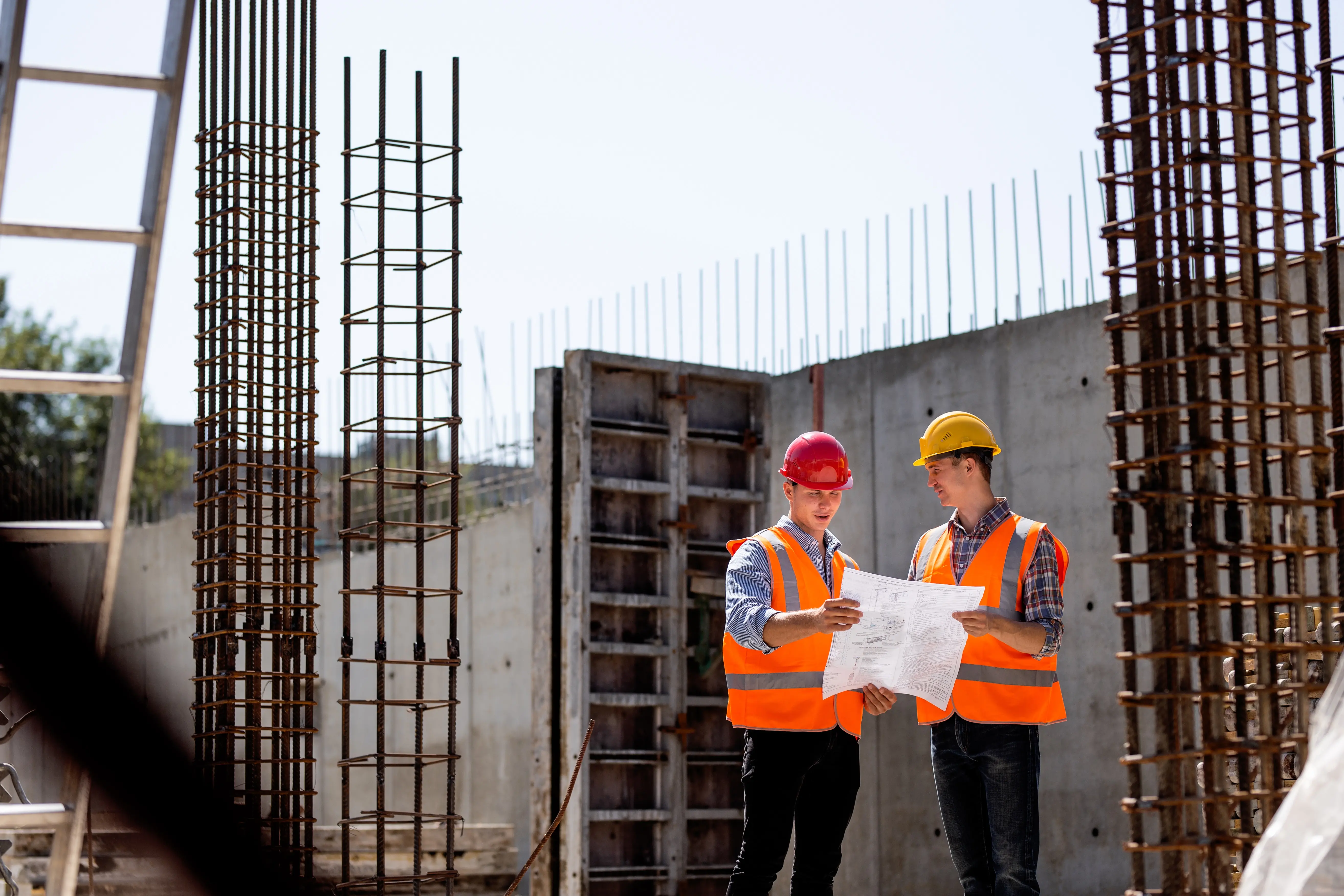 Zwei Bauarbeiter besprechen Projekt auf der Baustelle – DEMREX Beratung vor Ort