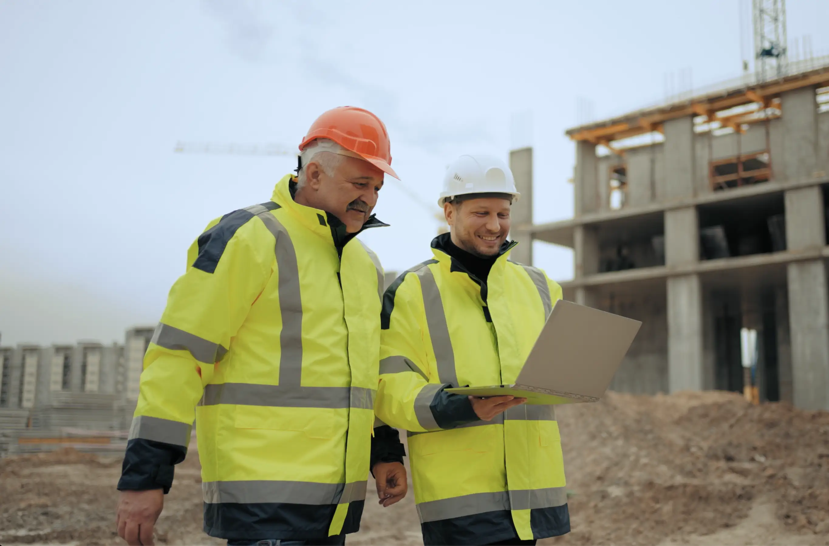 Zwei Bauleiter mit Laptop – Projektplanung und Koordination auf der Baustelle
