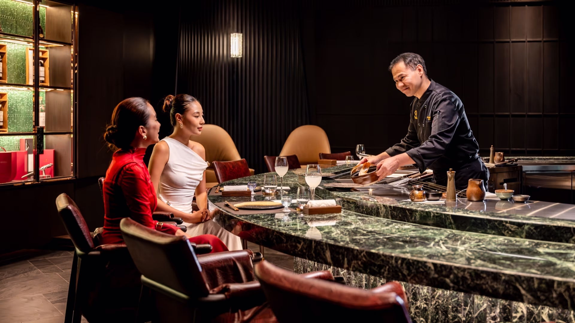 Guests watching a teppanyaki chef prepare dinner across the open grill