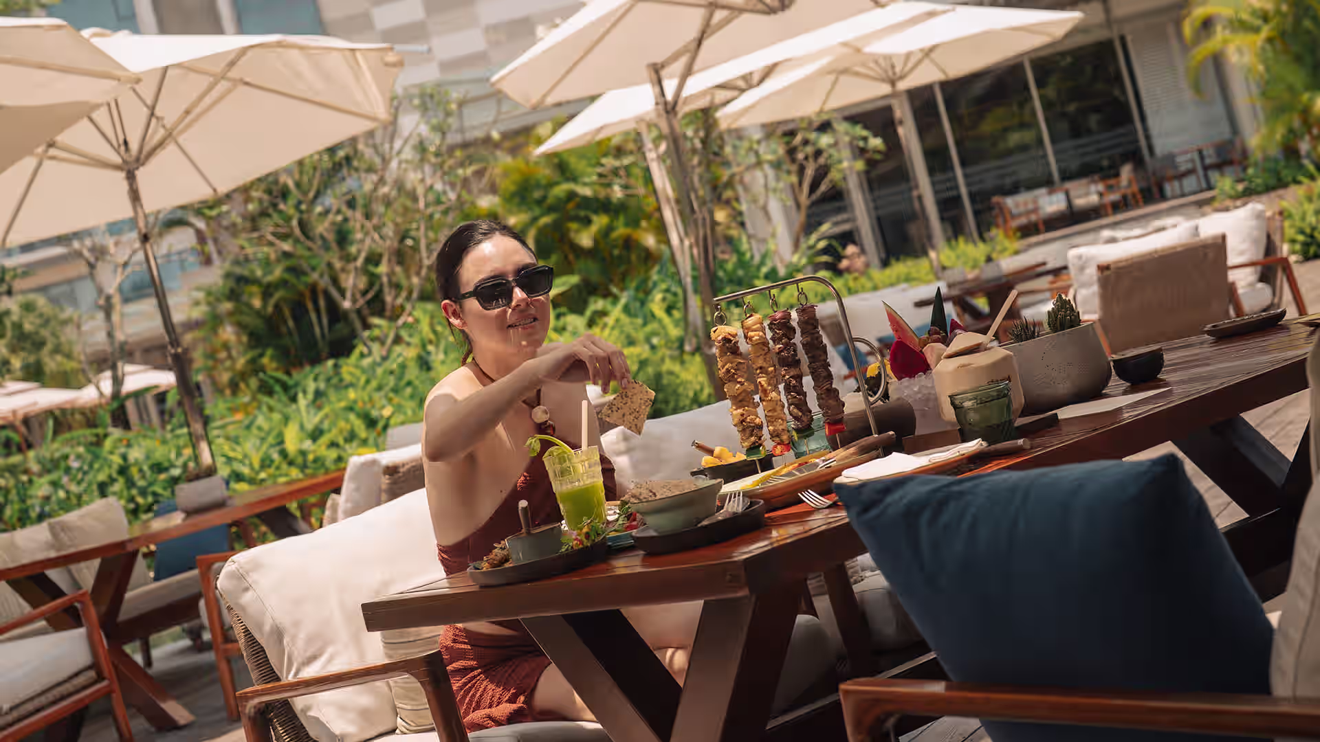 Relaxed poolside dining at Charred, New World Hoiana Hotel, where shaded seating and tropical greenery set the scene for easygoing gatherings