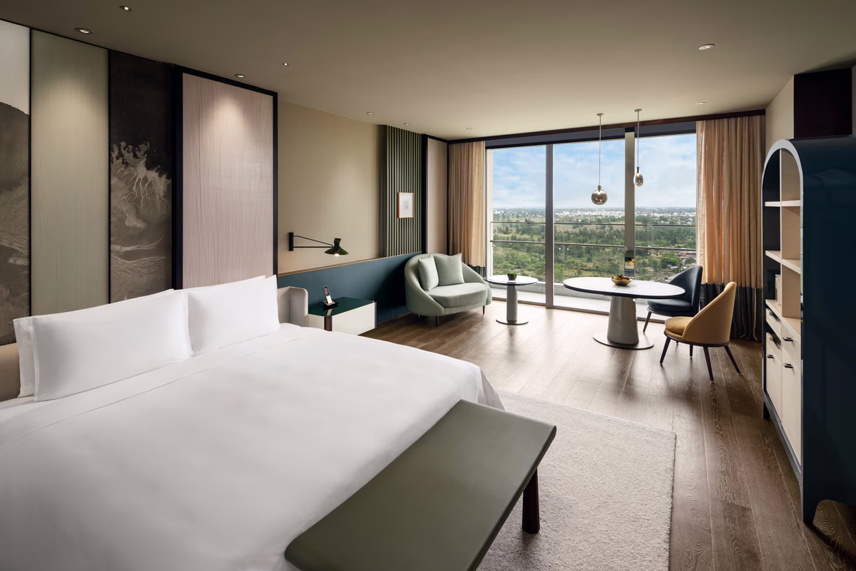 Deluxe Ocean View King room with a king bed, spacious living area and floor-to-ceiling windows overlooking the ocean at New World Hoiana Beach Resort