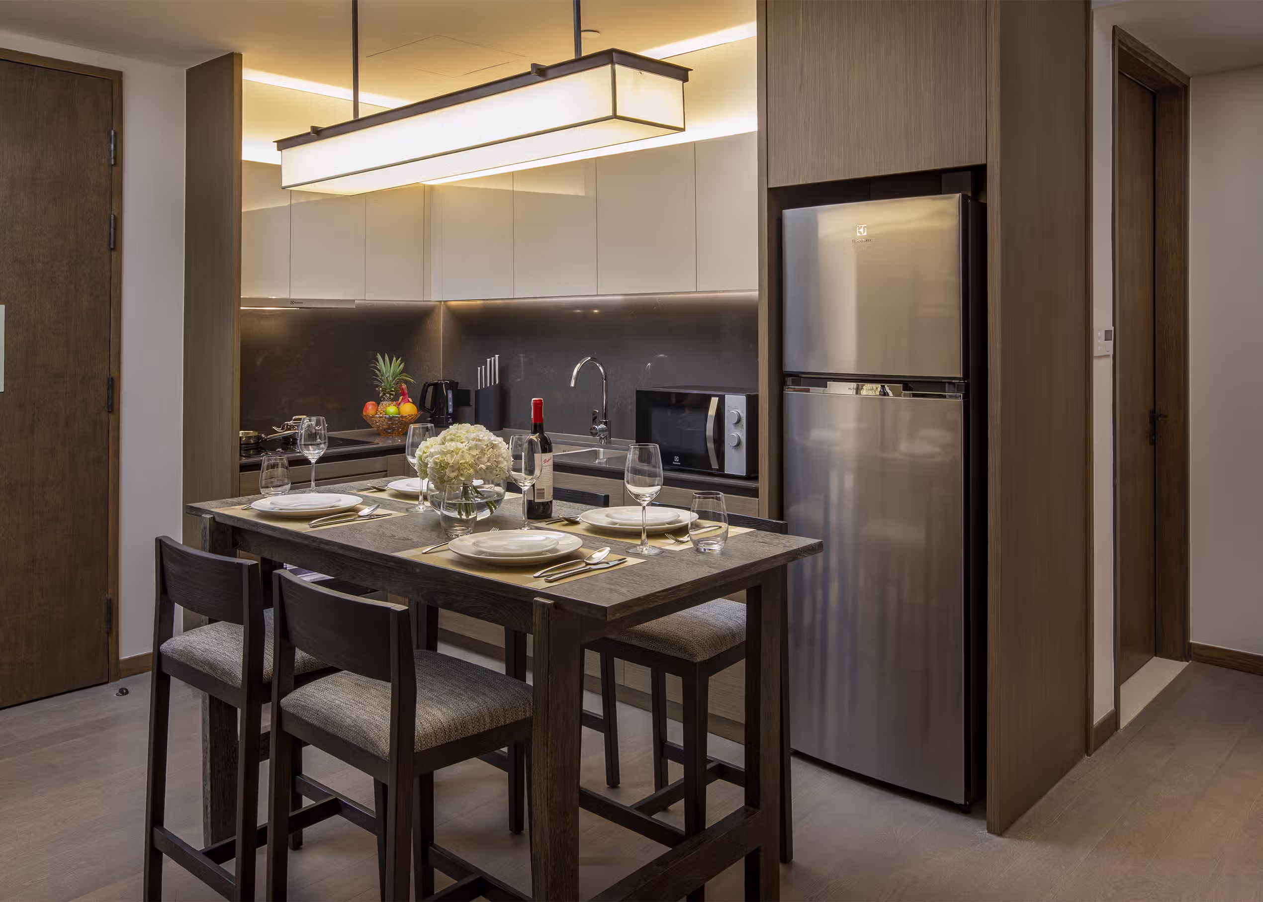 Fully equipped kitchen with an island dining table, oven, stove and refrigerator in the One-Bedroom Twin Residence at Hoiana Residences