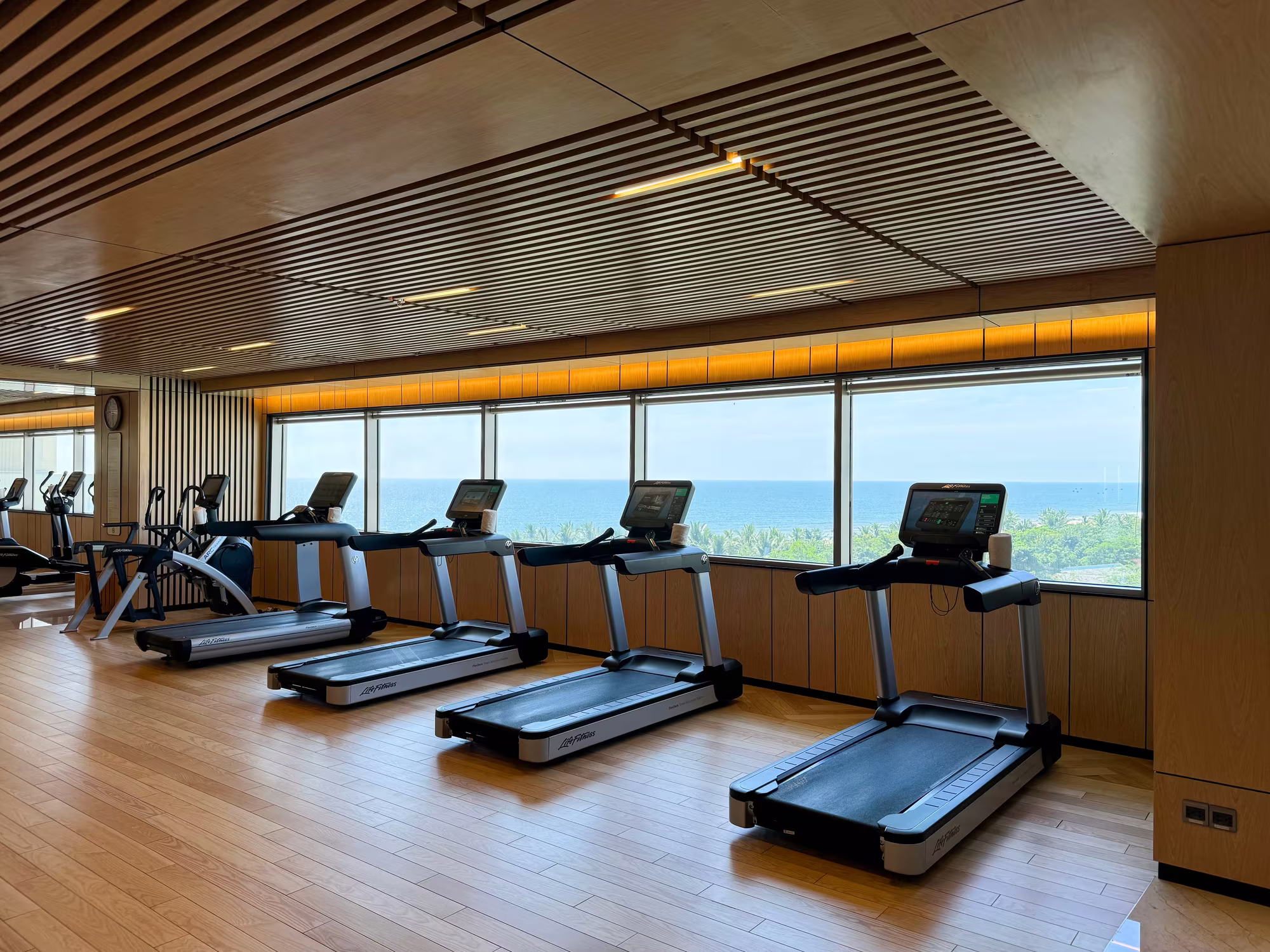 Modern fitness centre at Hoiana Resort & Golf with cardio and strength equipment in a bright, wood-accented space.