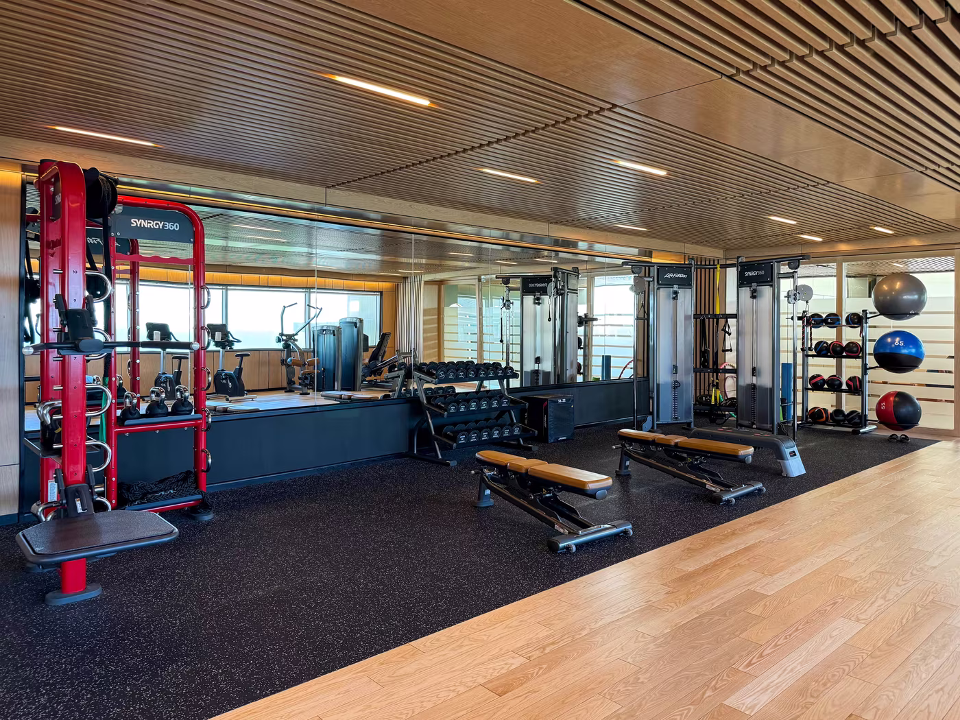 Light-filled fitness and yoga studios at Hoiana Resort & Golf, featuring modern cardio equipment, open workout spaces and sculpted timber ceilings.