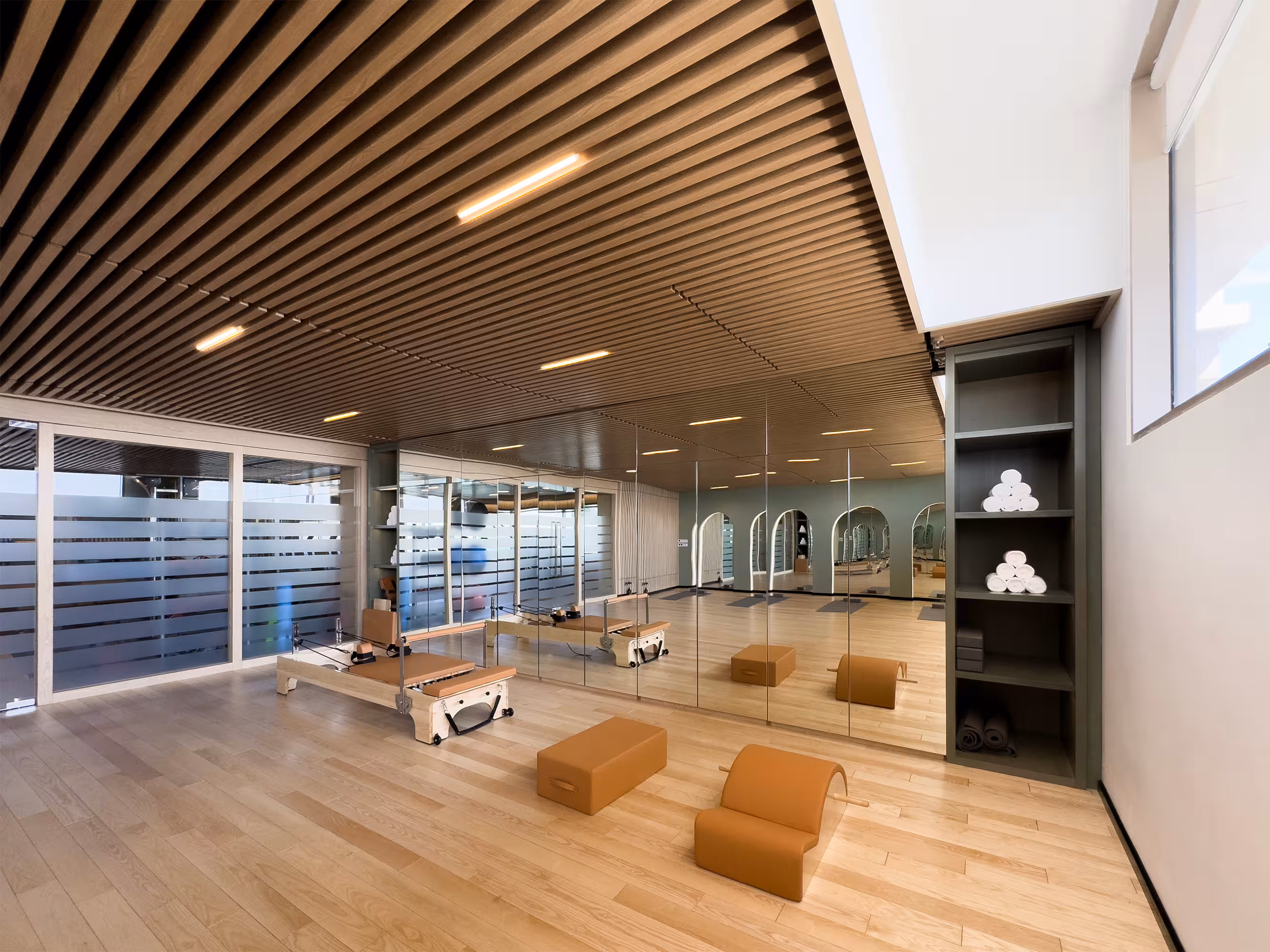 Spacious stretching area with full-length mirrors, wooden exercise steps and a warm timber ceiling.