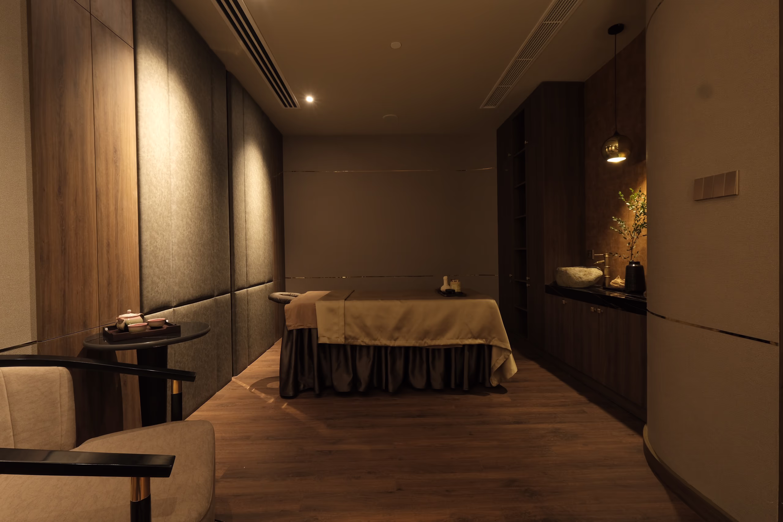 Serene massage room at Tinh Spa, styled with natural wood, gentle lighting and a private treatment bed.