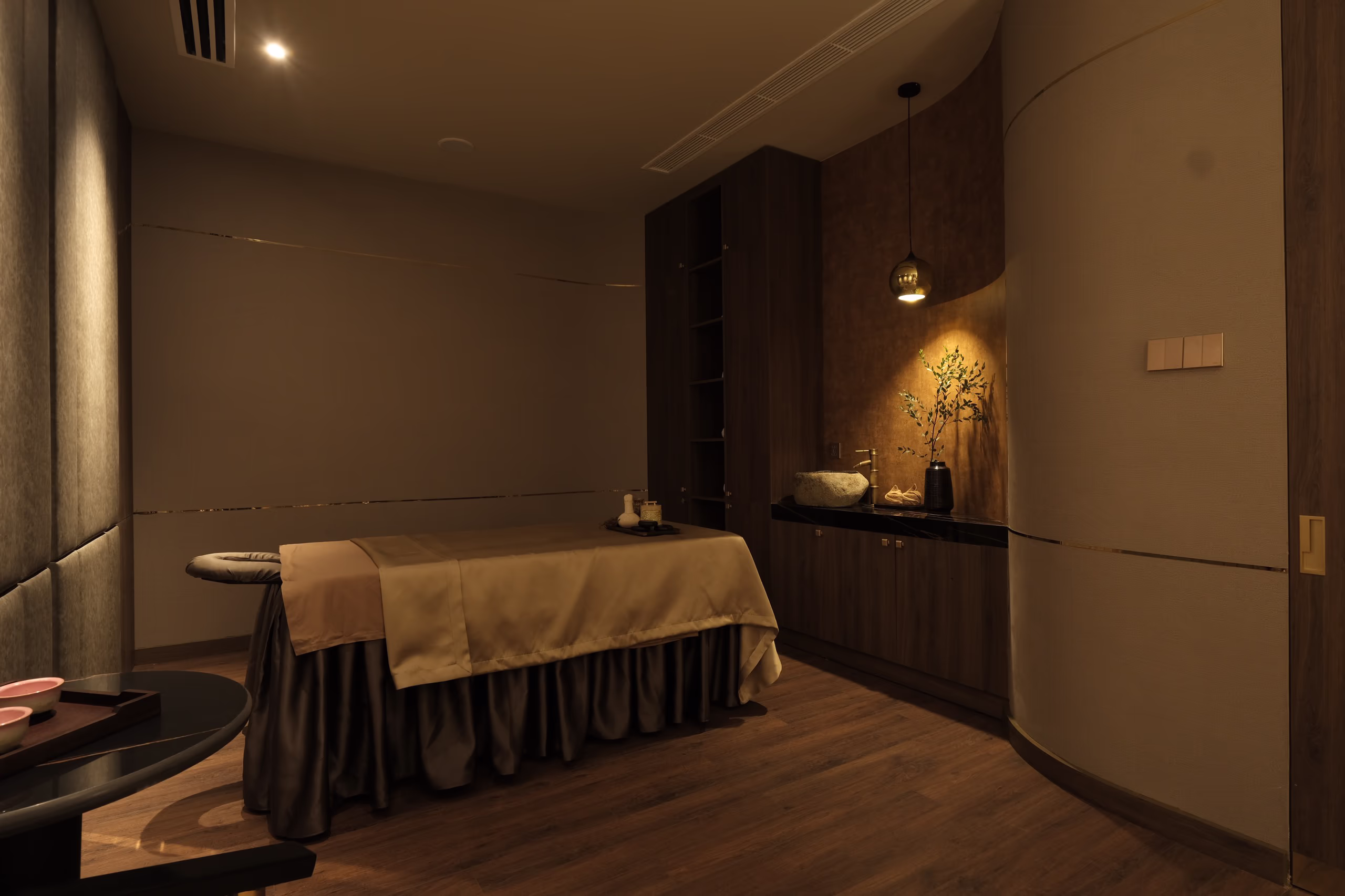 Private treatment room at Tinh Spa, featuring a massage bed, warm lighting and calming neutral interiors.