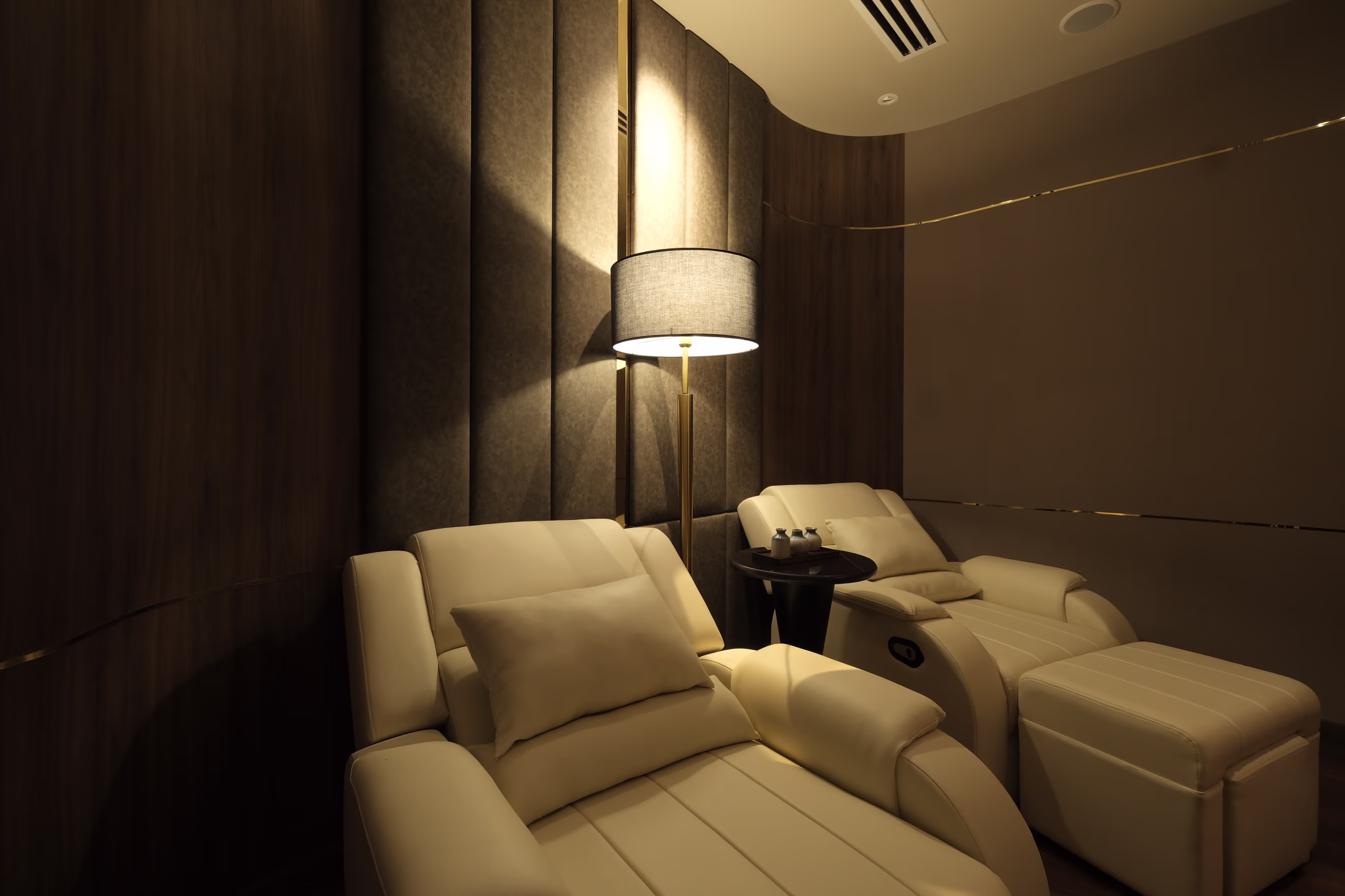 Quiet relaxation lounge at Tinh Spa with cushioned recliners, soft ambient lighting and dark wood accents.