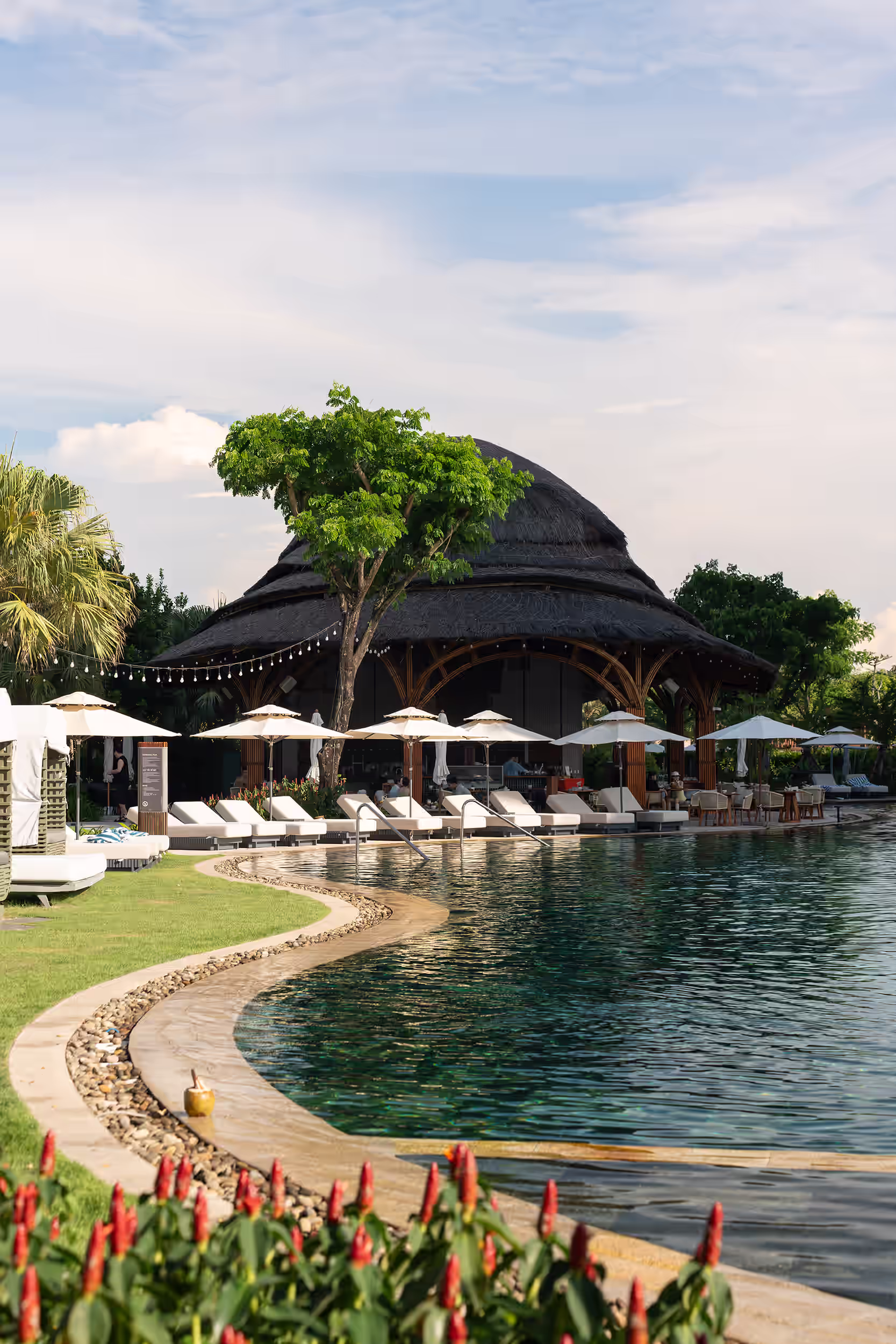 Spacious family swimming pool at Hoiana featuring fun pink flamingo floats and a tropical landscape for guests at Hoiana Hotel & Suites and New World Hoiana Beach Resort.