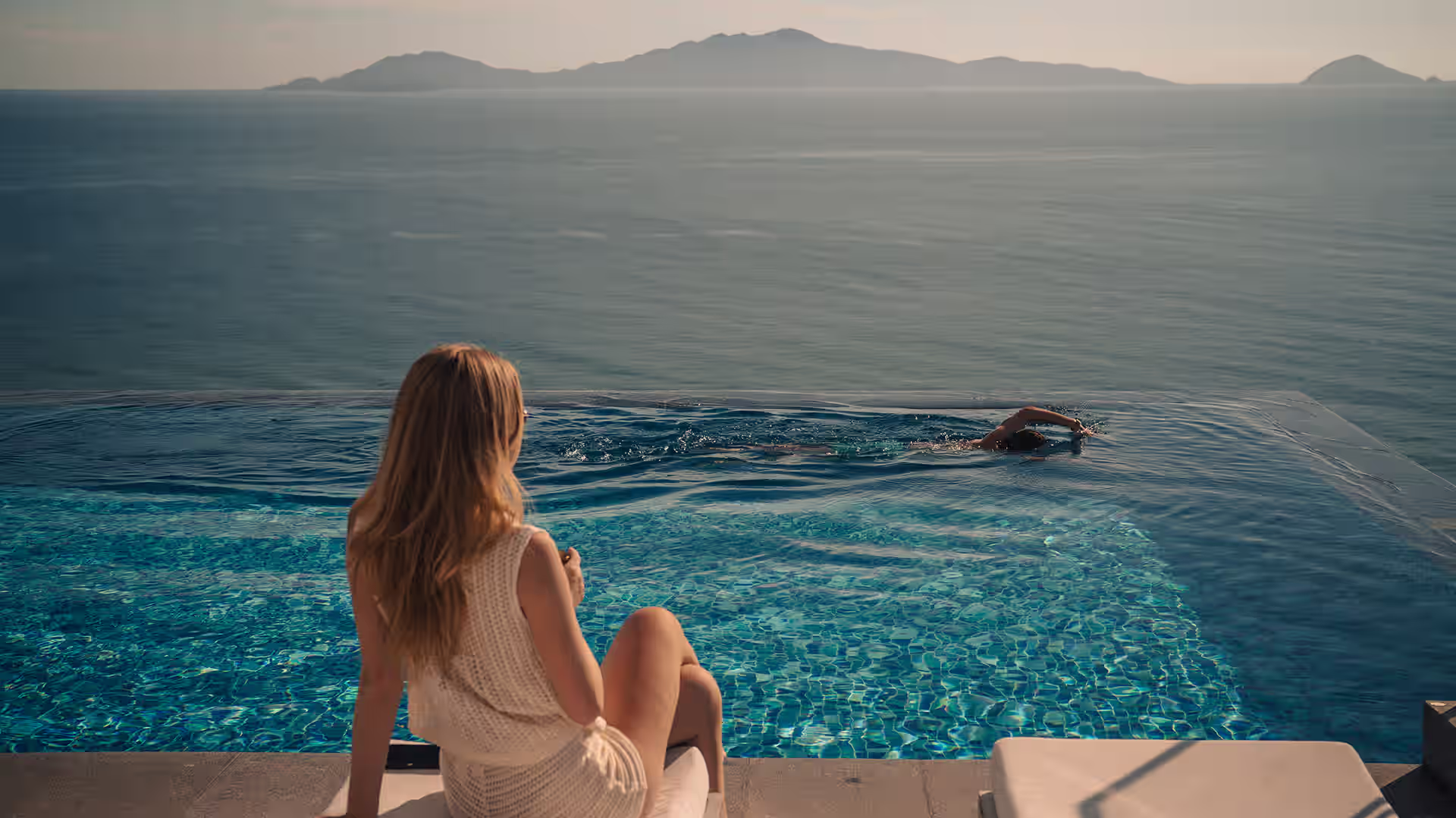 Guests enjoying the infinity pool at Hoiana Hotel & Suites, overlooking the sea and distant Cù Lao Chàm Island.