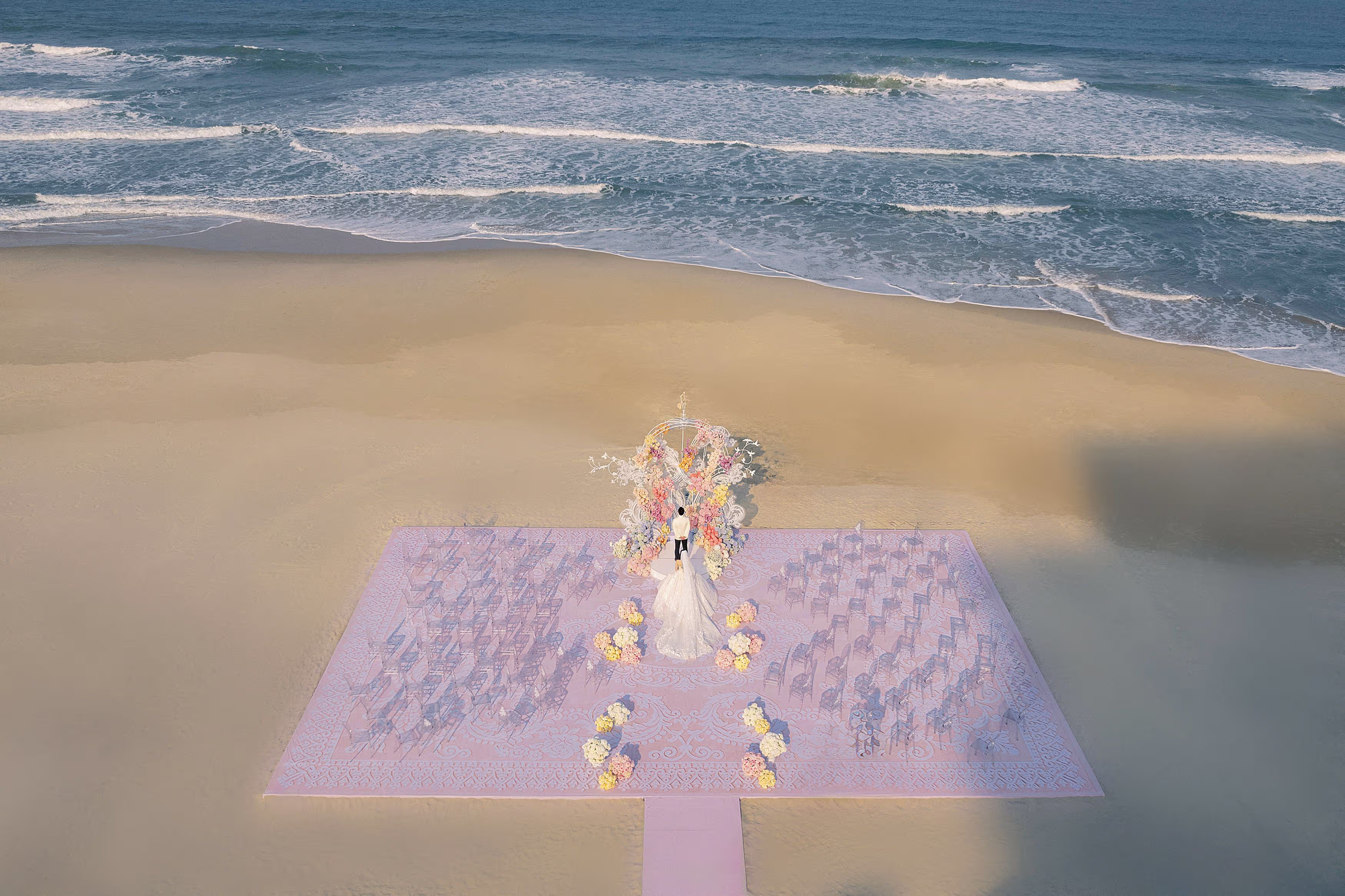 A lavender wedding aisle and delicate floral details create a softly styled ceremony setting beside the water