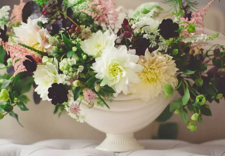 Elegant floral arrangement with white and pale pink flowers in ceramic vase.