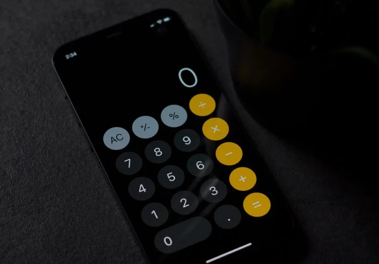 Dark mode calculator app on smartphone screen with yellow and gray buttons.