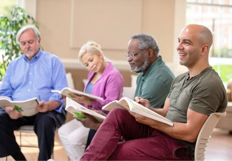 Diverse group of seniors reading books together in a bright room.