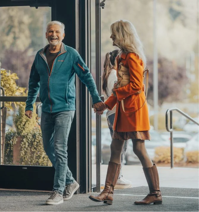 Older couple smiling and talking together near glass door entrance