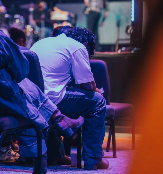 People sitting in dimly lit venue with blue and purple lighting