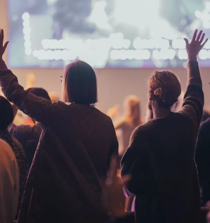 Audience raising hands at concert or conference with blurred stage background