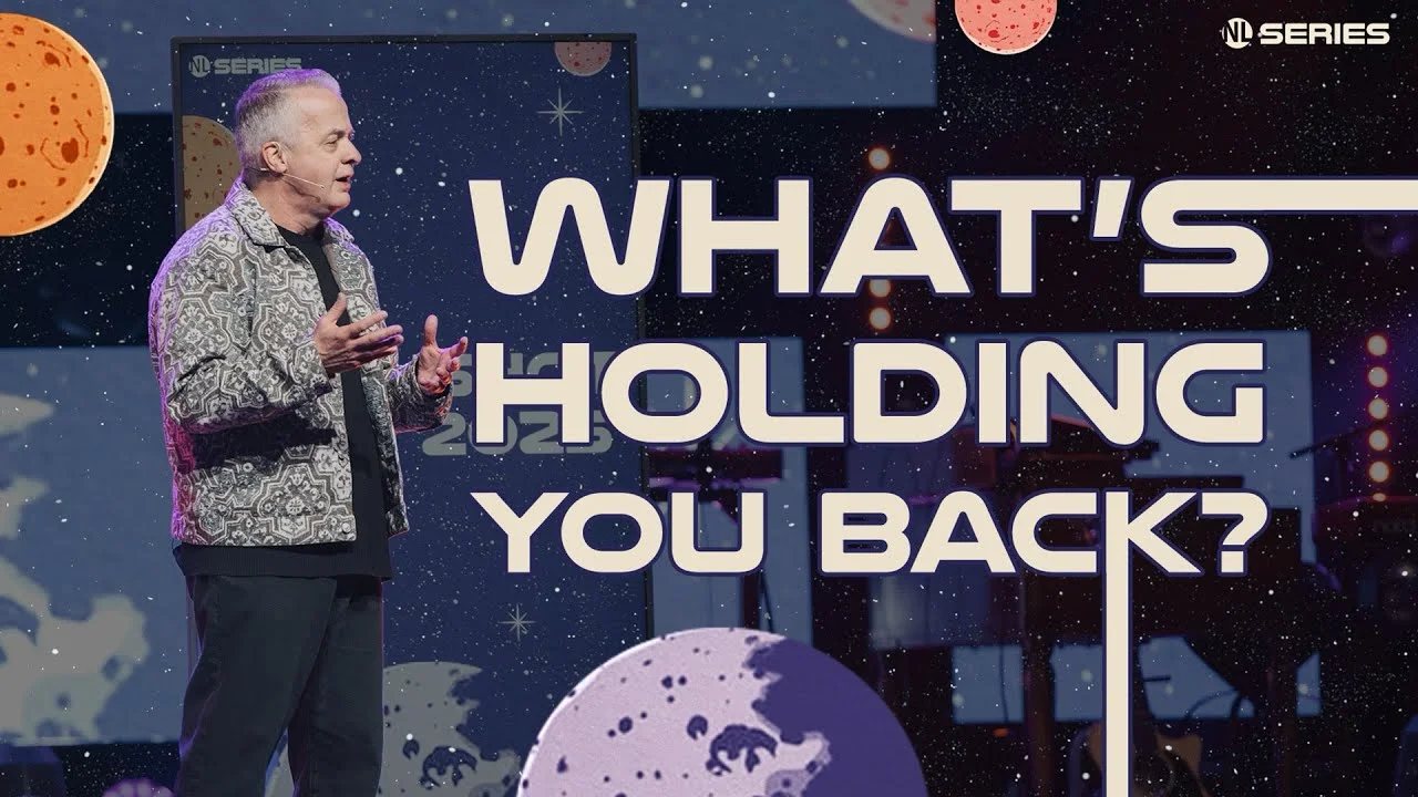 Speaker gesturing on stage with cosmic-themed background and bold text saying "What’s Holding You Back?" from NL Series.