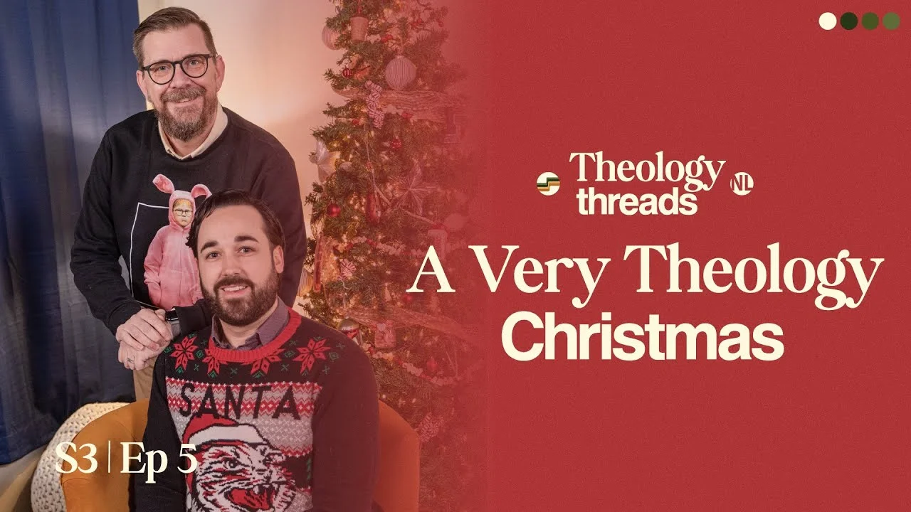 Two men in festive sweaters posing by Christmas tree for Theology Threads.
