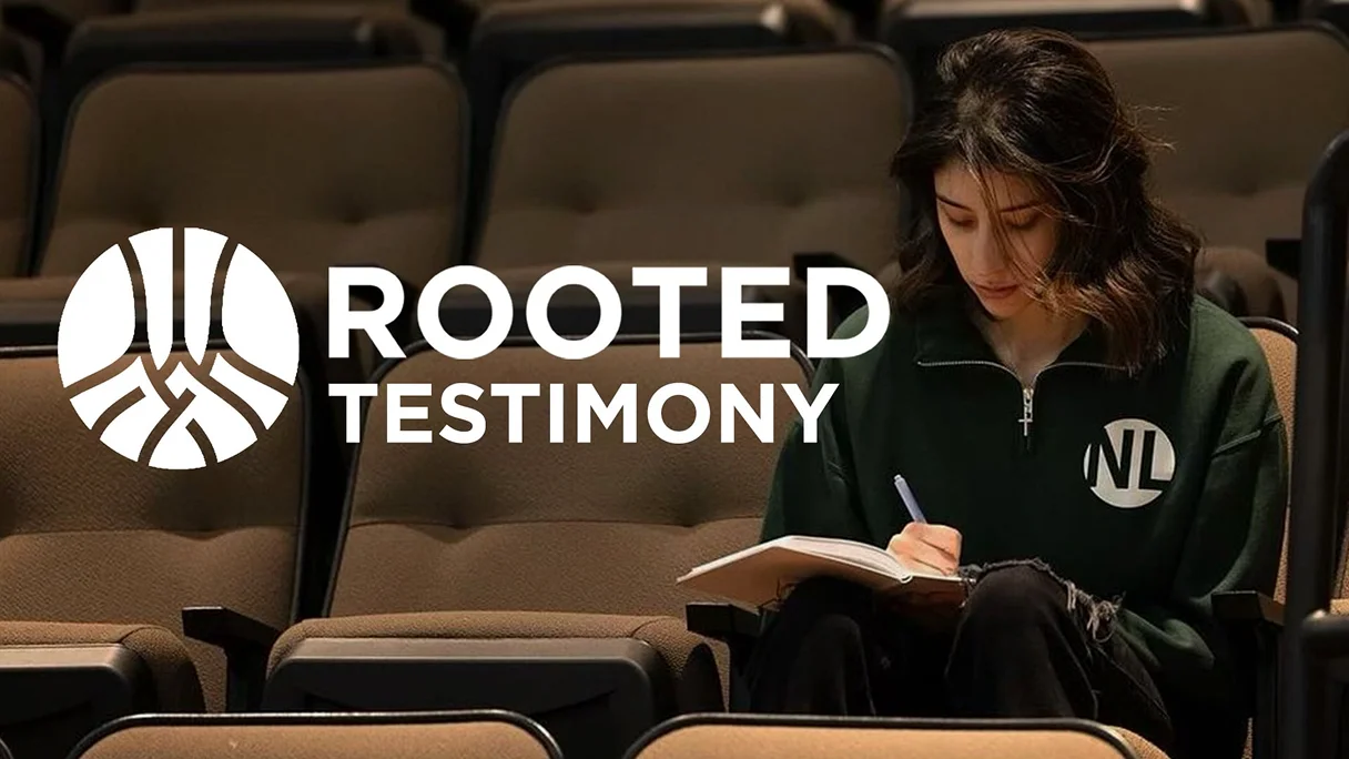 Woman writing in a notebook during Rooted testimony event inside a church auditorium.