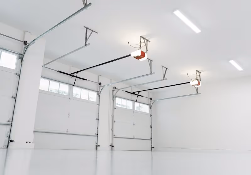 Multiple commercial grade garage doors viewed from inside the warehouse.