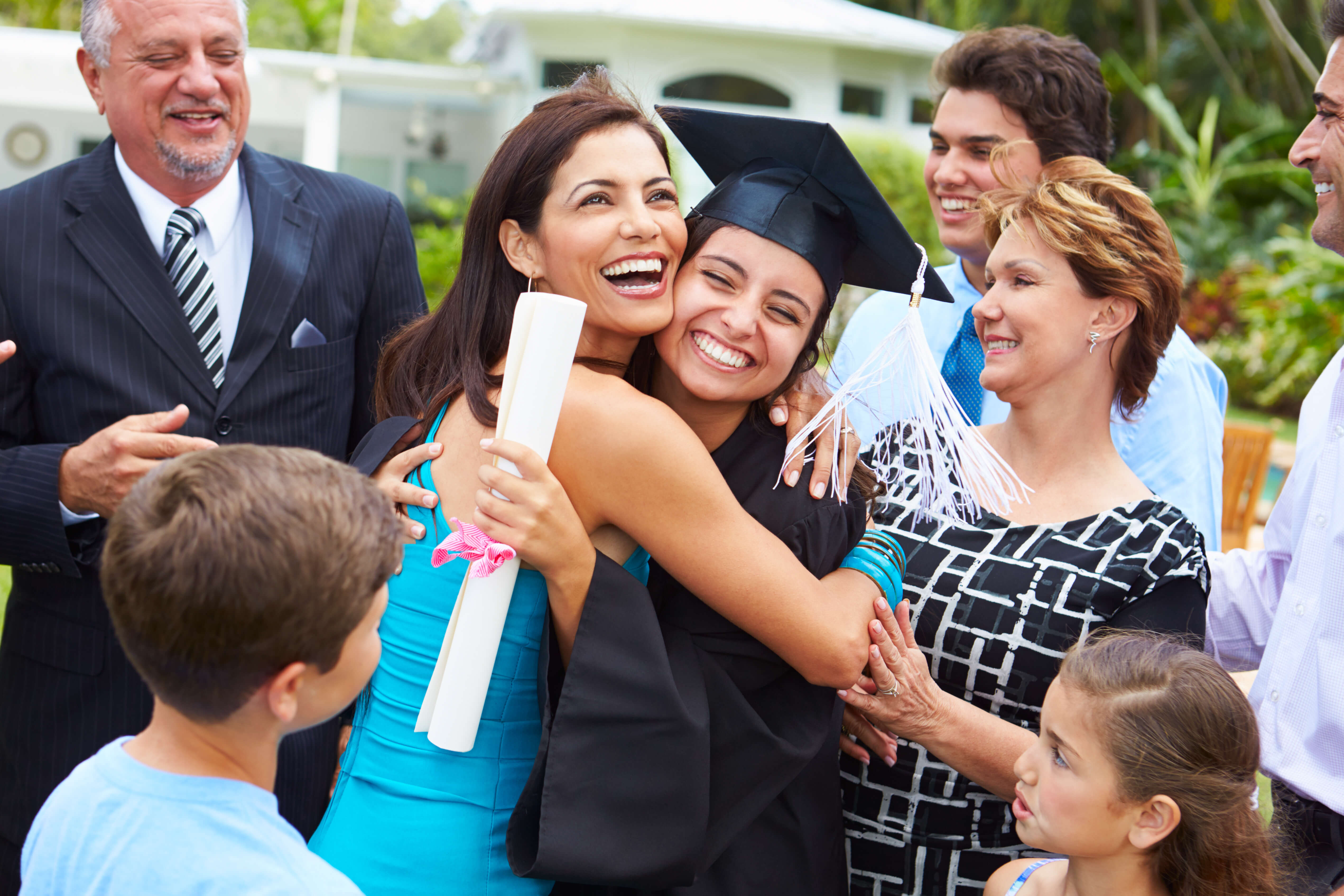 8 people mom dad and siblings at their sister's graduation along with grandparents.