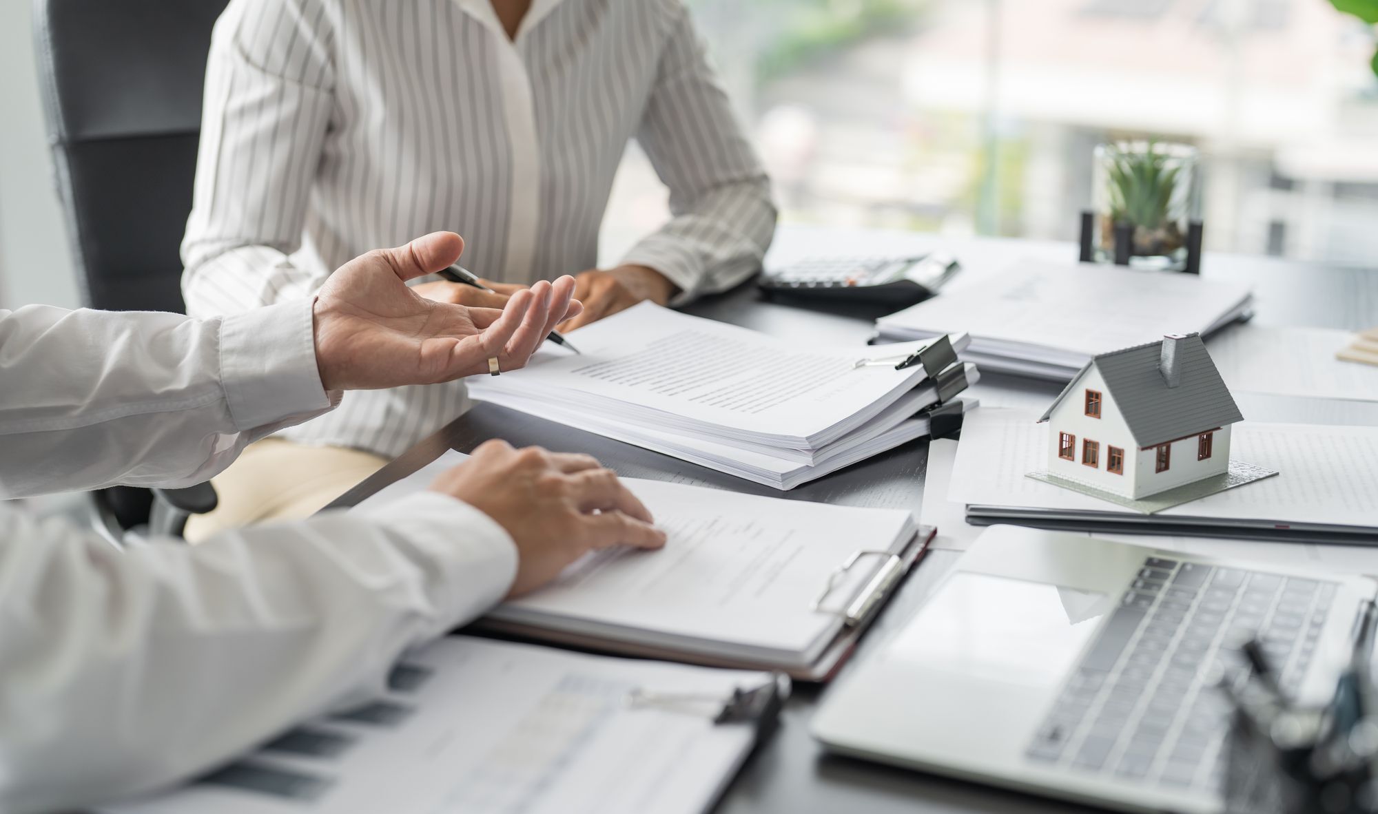 Man and Women at a table filled with paperwork, reviewing finances for home renovation.