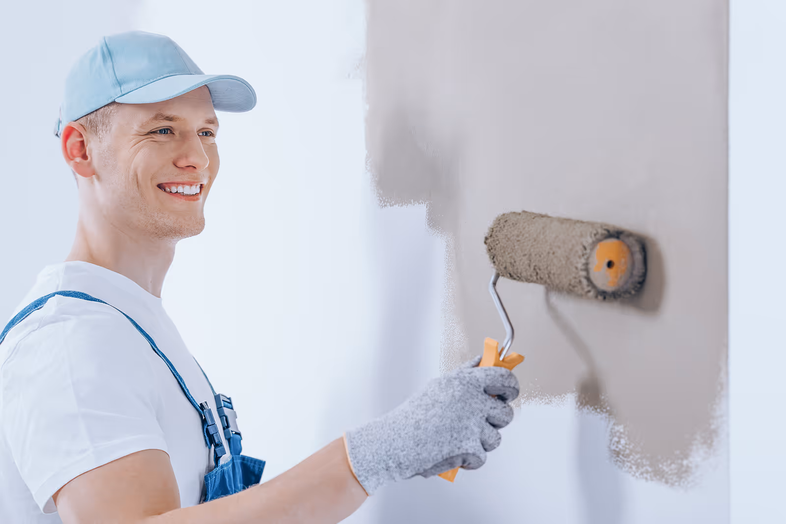 Professional painter working on the interior wall of a home with a paint roller.