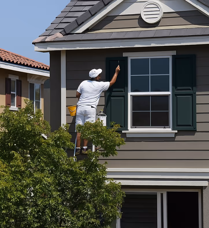 Professional house painter working on an exterior window shudder of a home.