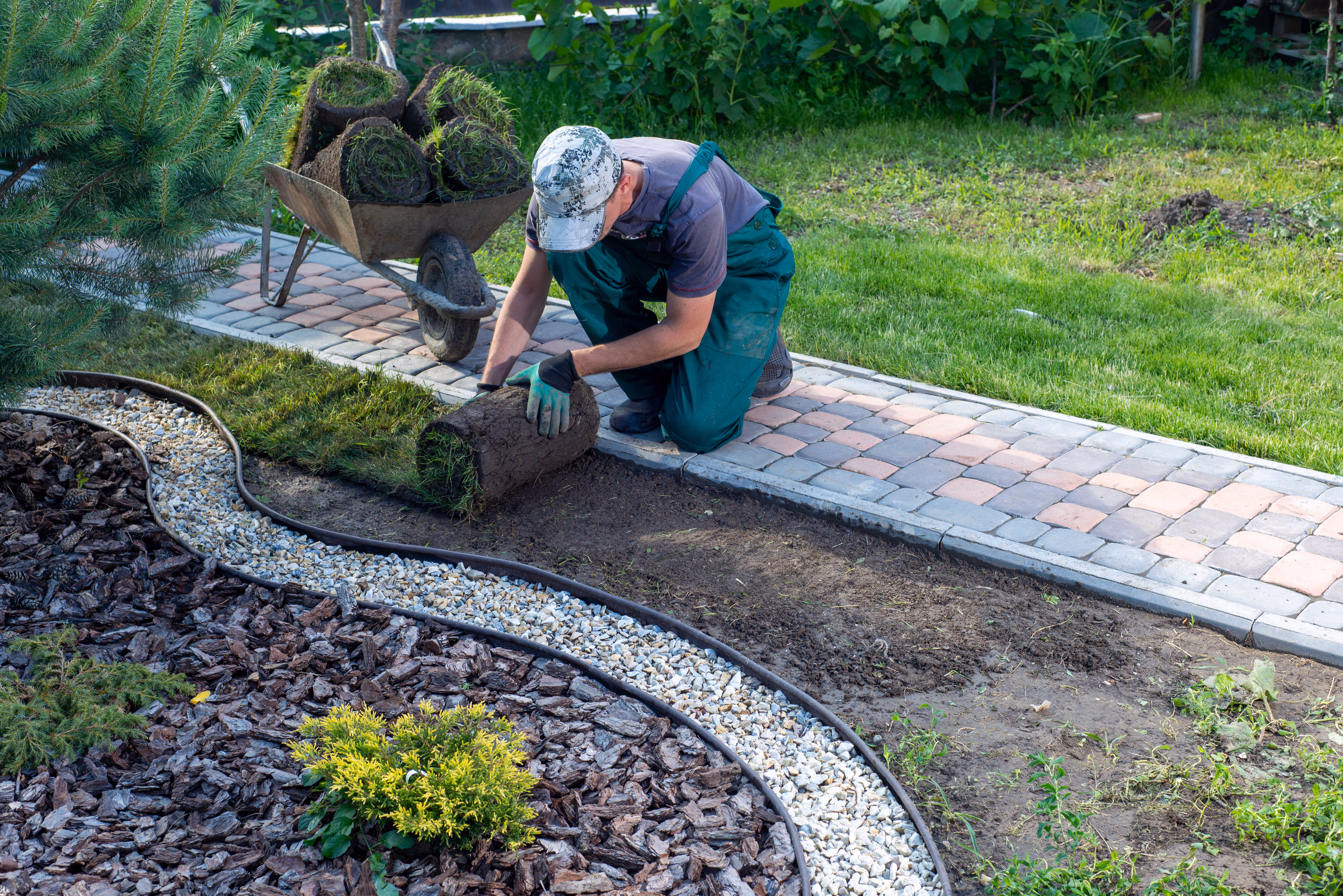 Landscaper laying sod in a residential garden.