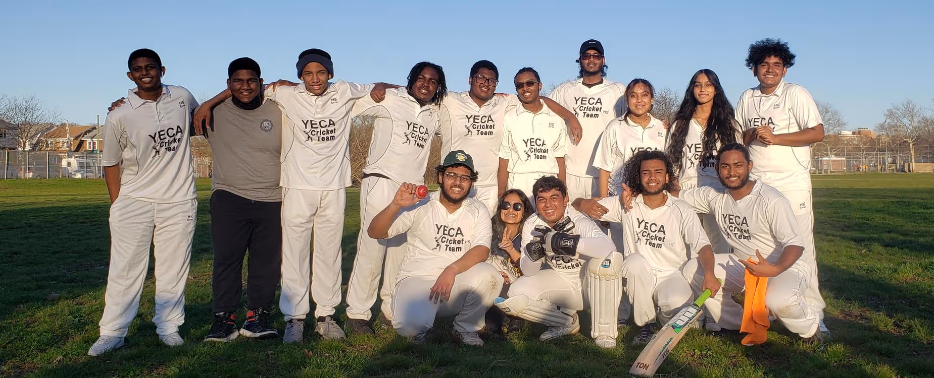 Students in matching white uniforms posing for a team photo on a grassy field
