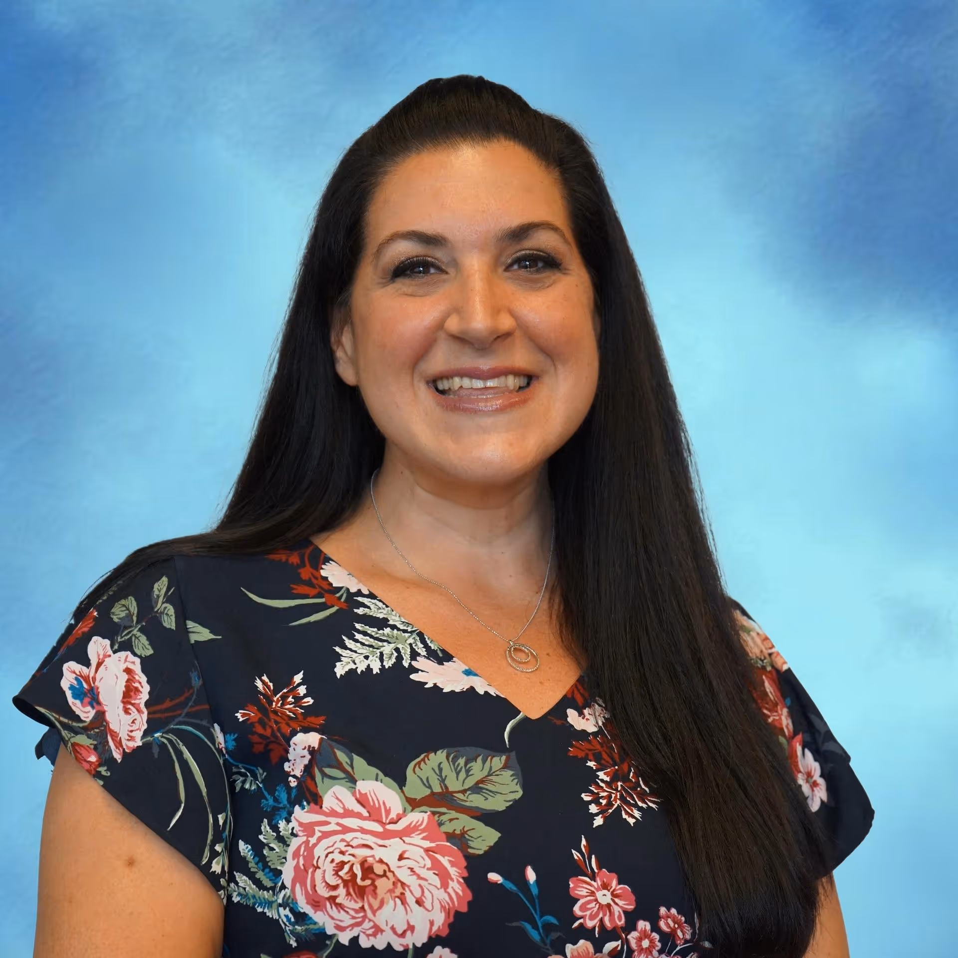 Professional headshot of a woman smiling in front of a blue background