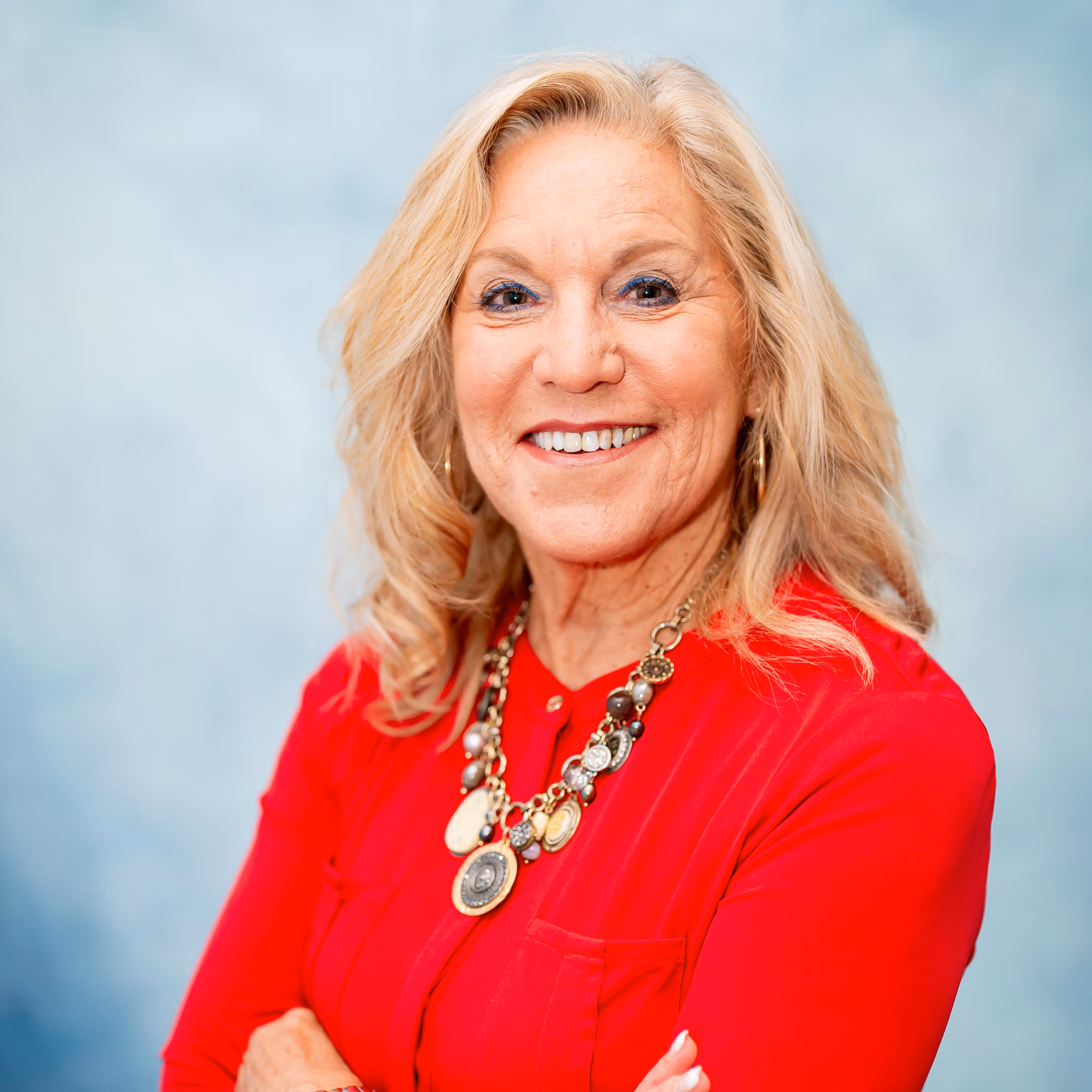 Professional headshot of a woman smiling in front of a blue background
