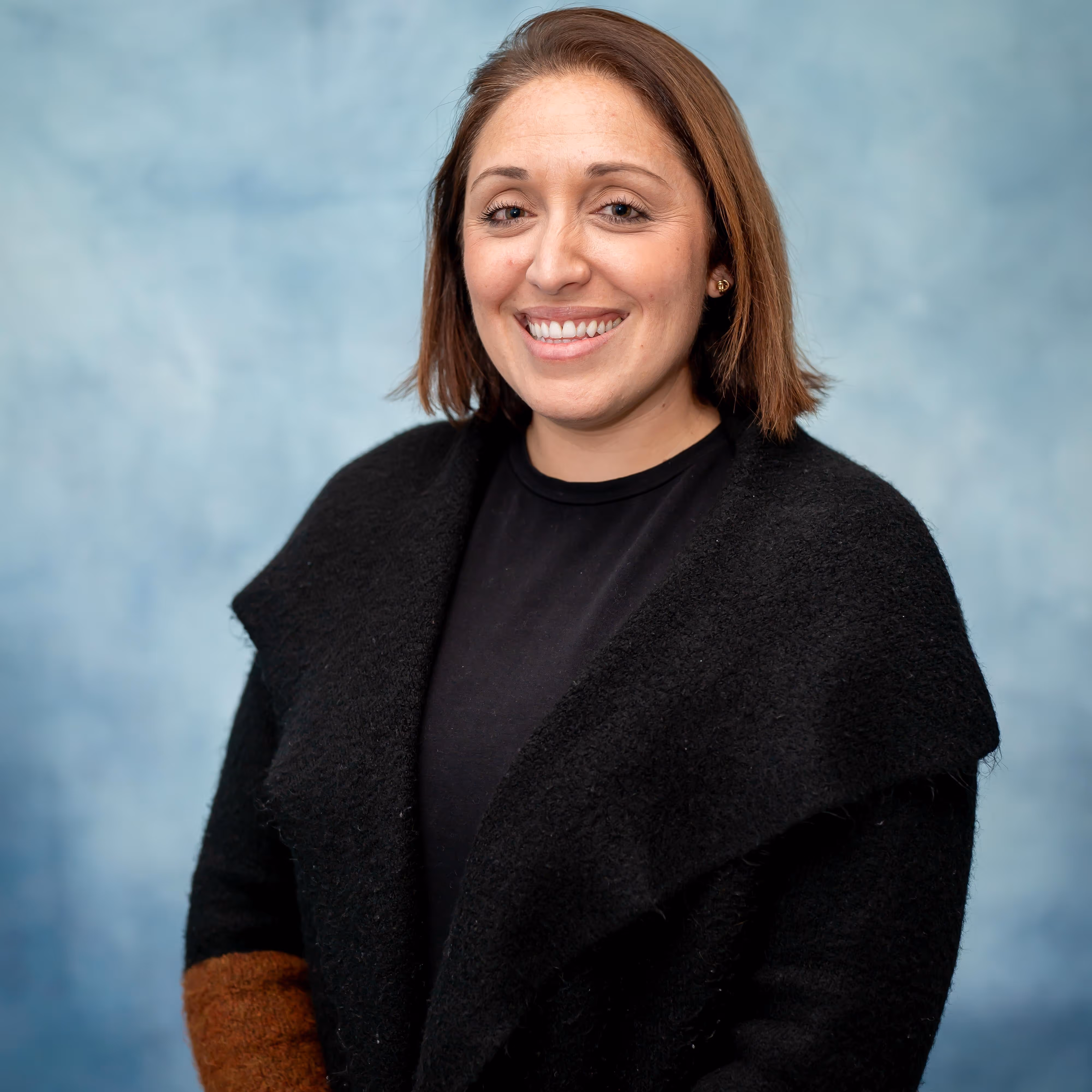 Professional headshot of a woman smiling in front of a blue background.