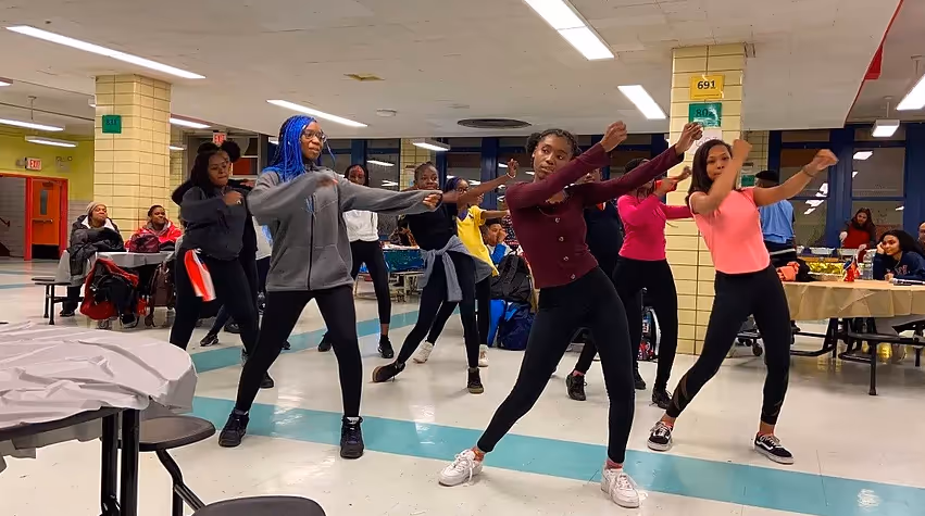 Students practicing a dance routine indoors.
