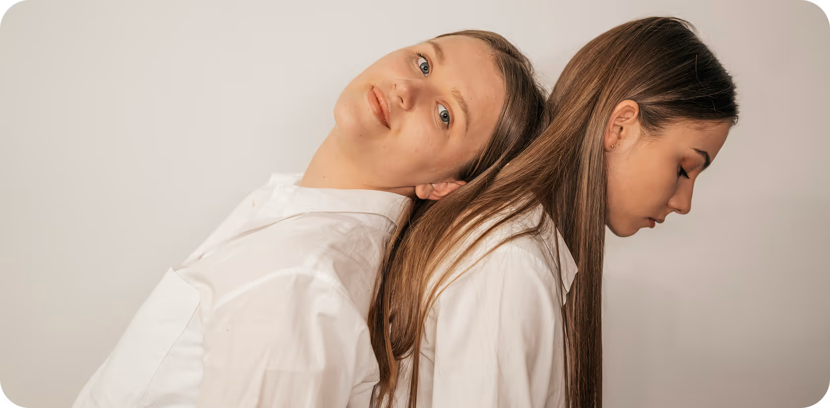 Δύο γυναίκες καθισμένες πλάτη με πλάτη, ακουμπισμένες η μία στην άλλη, συμβολίζοντας υποστήριξη, συνεργασία και εσωτερική ισορροπία.