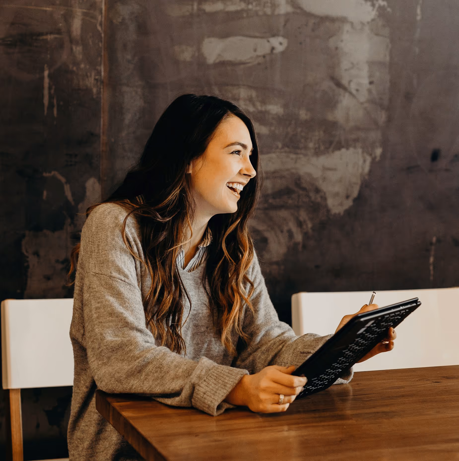 «Χαμογελαστή και χαρούμενη γυναίκα κάθεται σε γραφείο επαγγελματικού χώρου.»