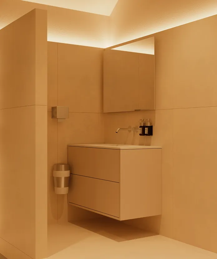 Minimalist bathroom corner with a floating vanity, wall-mounted faucet, mirror cabinet, and warm indirect ceiling lighting.