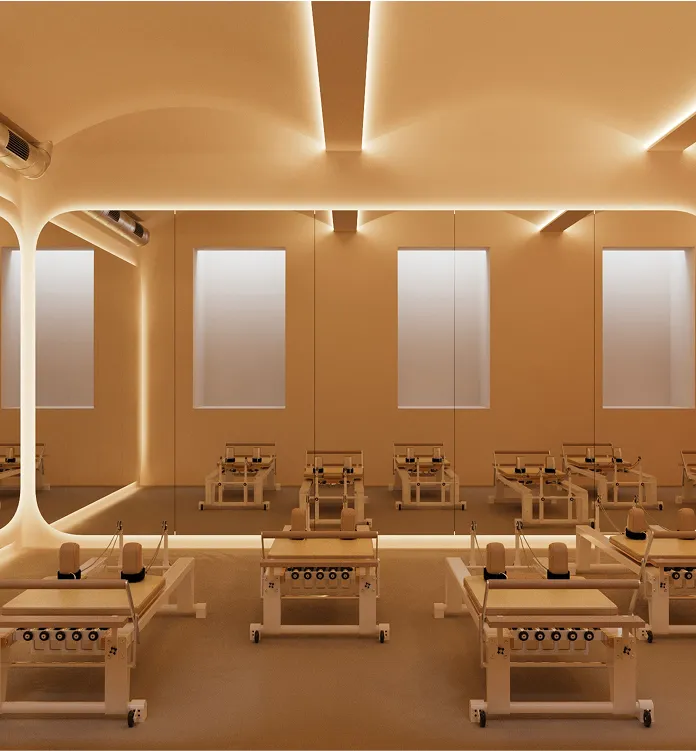 Minimalist Pilates studio with reformer machines, large mirrors, and soft warm lighting.