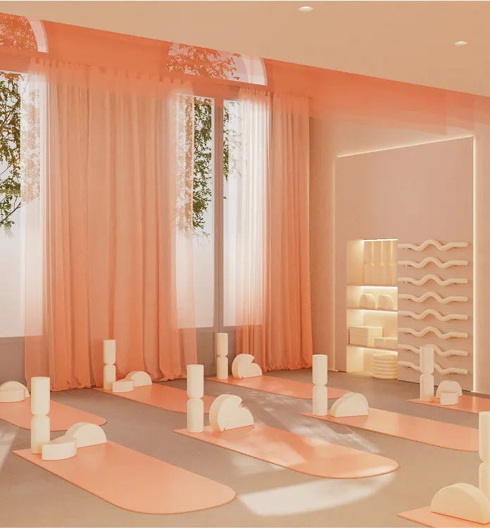 Bright yoga studio with peach-colored mats and geometric foam blocks arranged near sheer curtains and a large window.