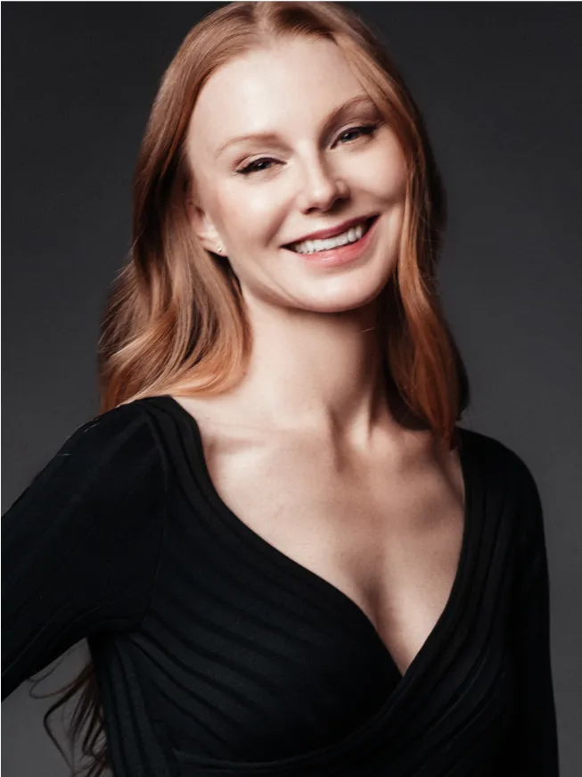 Female model in black sleeveless top smiling against dark studio background
