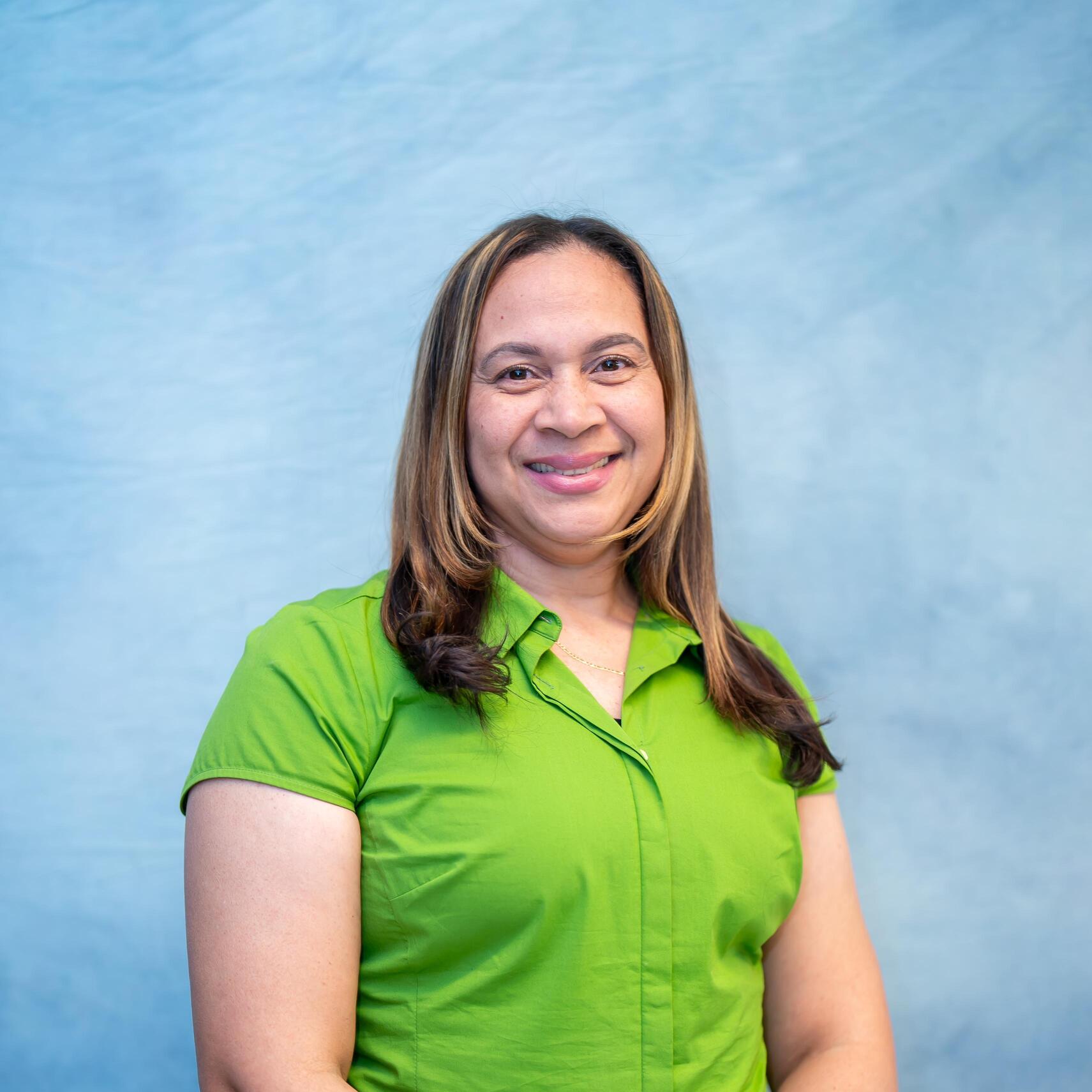 Staff member Lucy Santana smiling in green shirt