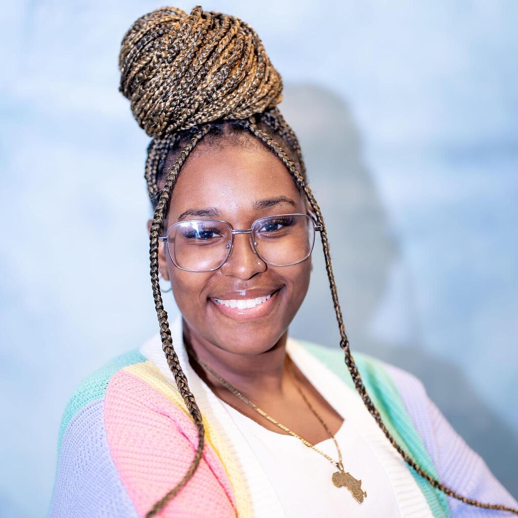Student wearing glasses smiling in colorful cardigan